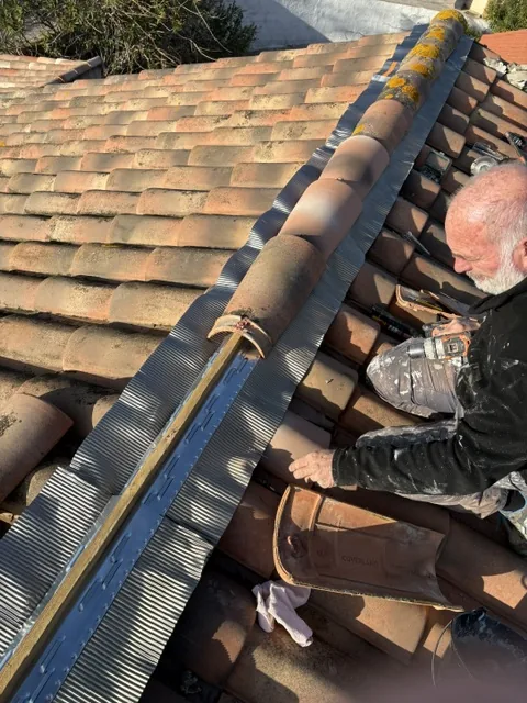Artisan LMpro Couverture posant un solin plomb en crête de toiture
